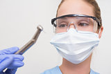 Dentist in surgical mask and protective glasses holding drill