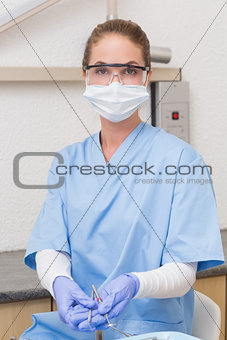 Dentist in blue scrubs holding dental tools