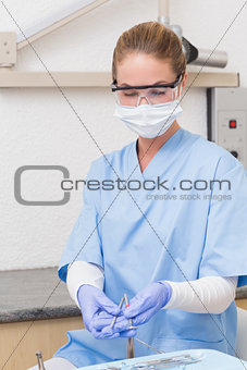 Dentist in blue scrubs holding dental tools