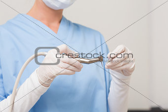 Dentist in blue scrubs holding drill