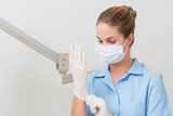 Dental assistant in mask pulling on gloves