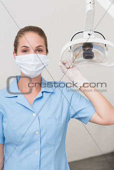 Dental assistant in mask holding light