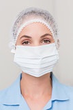 Dentist in surgical mask and cap looking at camera