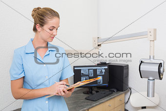Dental assistant writing in folder