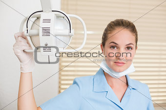 Dental assistant smiling at camera beside light