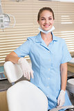 Dental assistant smiling at camera beside chair