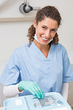 Dentist smiling at camera while picking up tools