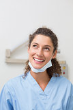 Dentist in blue scrubs smiling and thinking