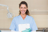 Dentist in blue scrubs holding clipboard