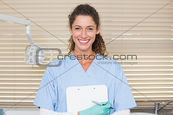 Dentist in blue scrubs holding clipboard