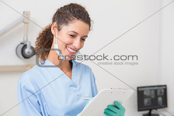 Dentist in blue scrubs writing on clipboard