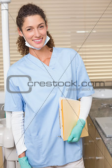 Dentist in blue scrubs smiling at camera