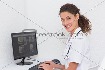 Dental assistant working on computer smiling at camera