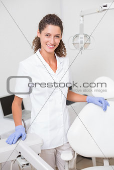 Dental assistant smiling at camera beside chair