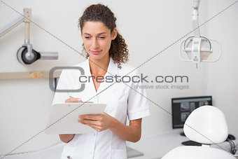 Dental assistant writing in clipboard