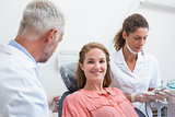 Dentist talking with patient while nurse prepares the tools