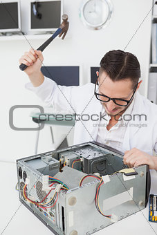 Angry computer engineer holding hammer over console