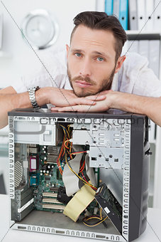 Sad computer engineer leaning on computer