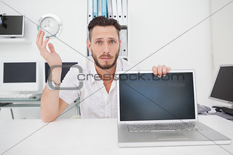 Confused computer engineer looking at camera with laptop
