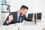 Angry businessman holding hammer over laptop