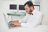 Nerdy businessman working on laptop at desk