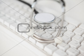 Stethoscope lying on white keyboard