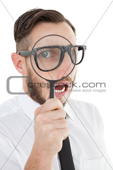 Nerdy businessman looking through magnifying glass