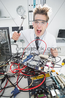 Angry computer engineer holding hammer over console