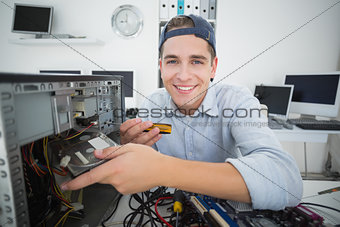 Smiling computer engineer working on broken console with screwdriver