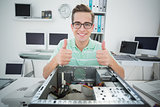 Smiling technician working on broken computer showing thumbs up