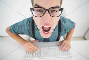 Casual angry businessman typing at his desk