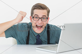 Nerdy businessman at his desk looking at laptop