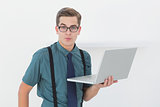 Nerdy businessman holding laptop looking at camera