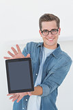 Nerdy businessman showing tablet pc smiling at camera