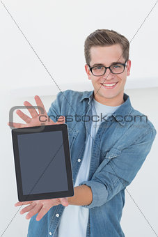 Nerdy businessman showing tablet pc smiling at camera