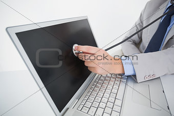 Technician listening to laptop with stethoscope