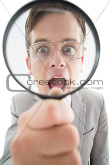 Excited businessman looking through magnifying glass