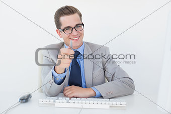 Nerdy businessman working on computer pointing at camera