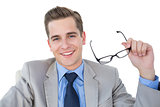 Smiling businessman holding his glasses
