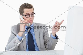 Nerdy businessman working on computer talking on phone