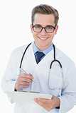 Smiling young doctor writing on clipboard