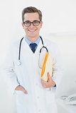 Smiling young doctor holding folder looking at camera