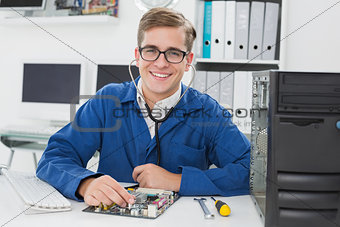 Smiling technician listening to cpu with stethoscope
