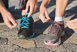 Couple tying their laces of running shoes