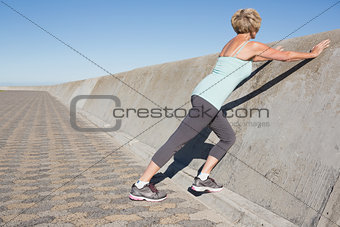 Active senior woman stretching on the pier
