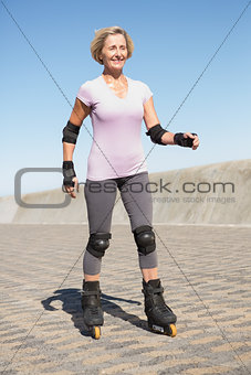 Active senior woman rollerblading on the pier