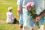 Senior man hiding flowers behind his back