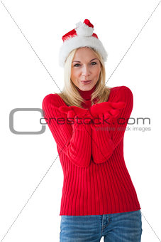 Festive blonde smiling at camera and blowing over hands