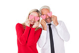 Silly couple holding hearts over their eyes
