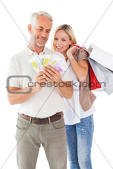 Happy couple holding shopping bags and cash